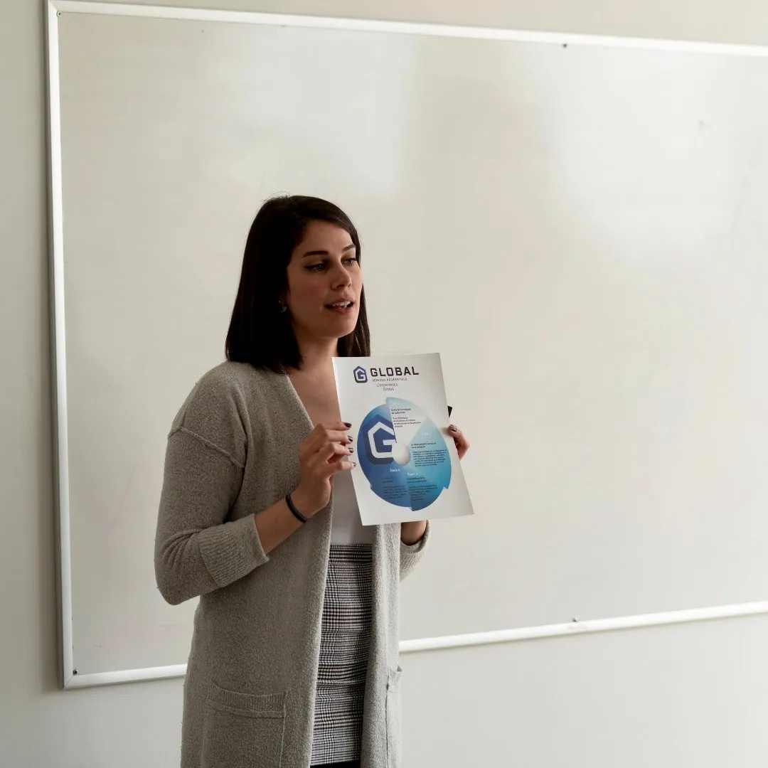 Woman presenting a document titled 'Global' in front of a whiteboard.